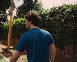 Man walking outdoors in Mendoza, Argentina, surrounded by lush greenery. Rear view in casual setting.
